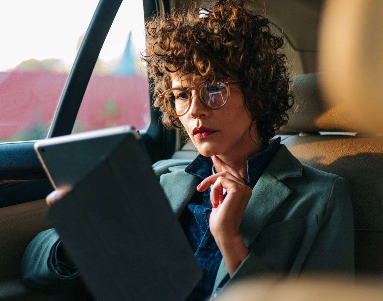 Woman with curly hair and glasses looking at a tablet