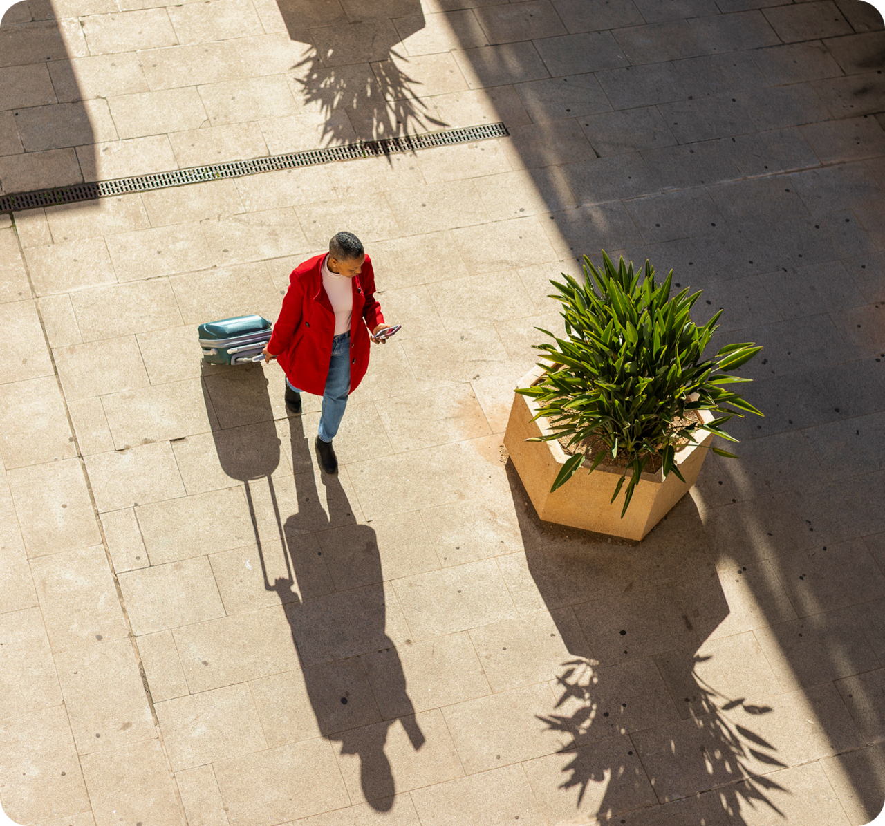 Person in a red jacket pulling a suitcase