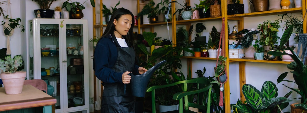 Woman in a dark apron watering plants