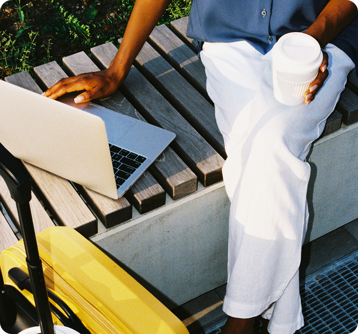 Person sitting on an outdoor bench working on a laptop