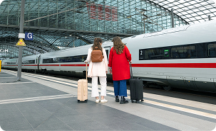 Two travelers standing on a high-speed train platform at a modern European station.