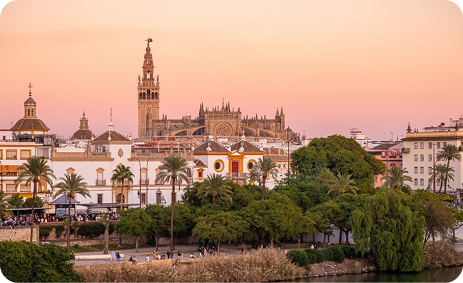 Aerial view of Seville, Spain, featuring Seville Cathedral and Giralda bell tower at sunset.