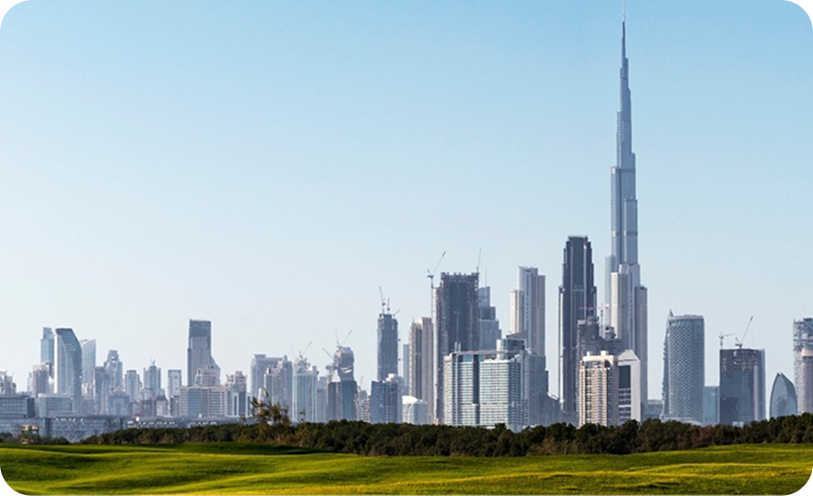 Dubai city skyline featuring the Burj Khalifa and other skyscrapers rising behind lush green fields under a clear blue sky.