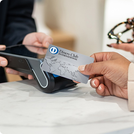 Customer tapping a silver loyalty card on a point-of-sale payment terminal during a transaction.